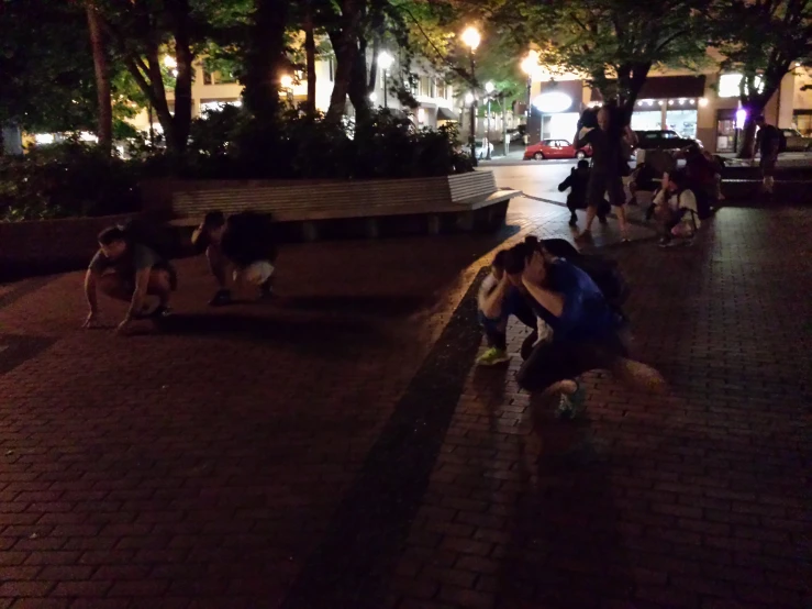 a group of people kneeling down on a brick road in the dark