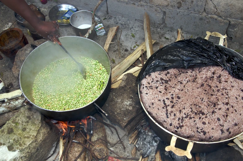 two pans filled with food sitting next to fire