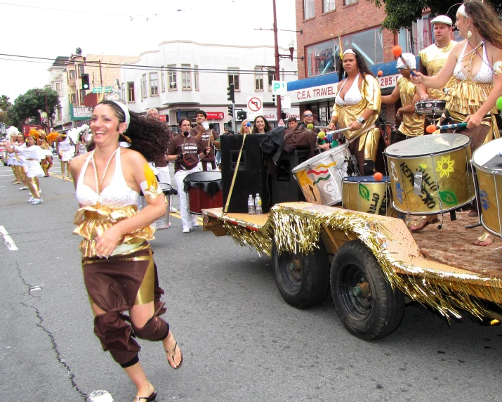 a parade of dancers in gold costume and some drum players