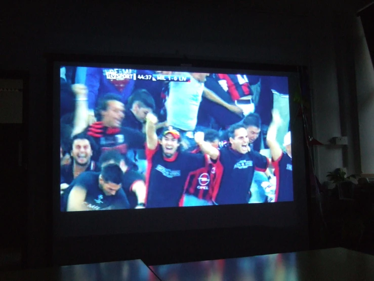 the television is lit up on and showing an image of a football team
