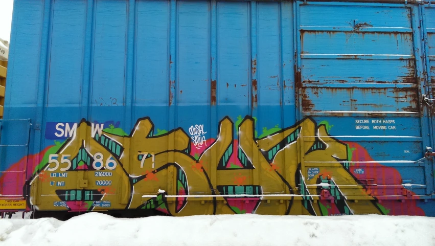 a blue trailer with some yellow graffiti on it