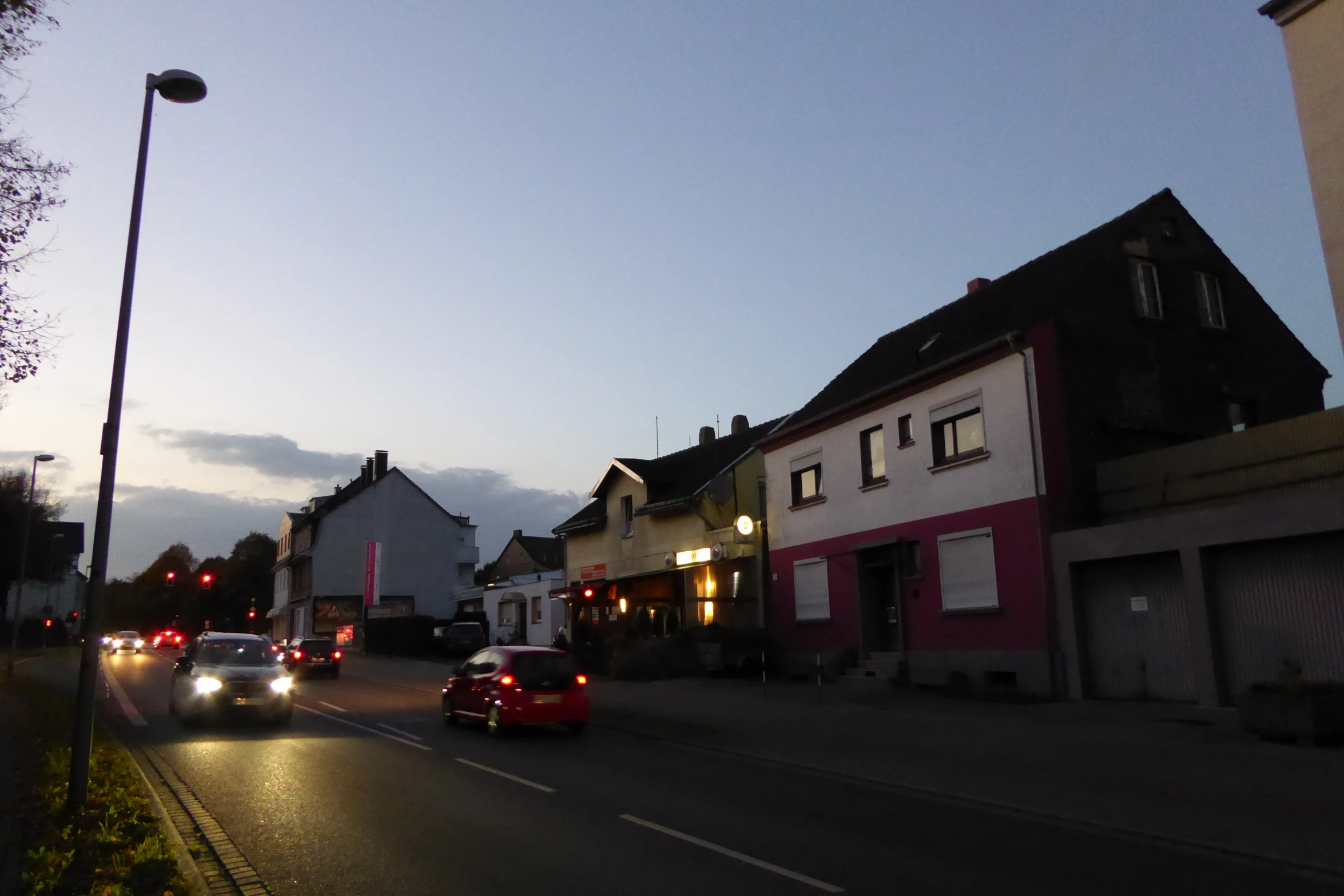 the street at twilight has some cars driving on it