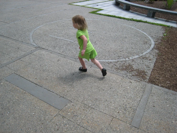 a little girl that is walking across some cement