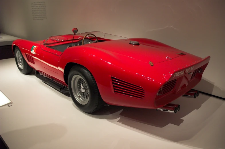 an old red sports car displayed on a white floor