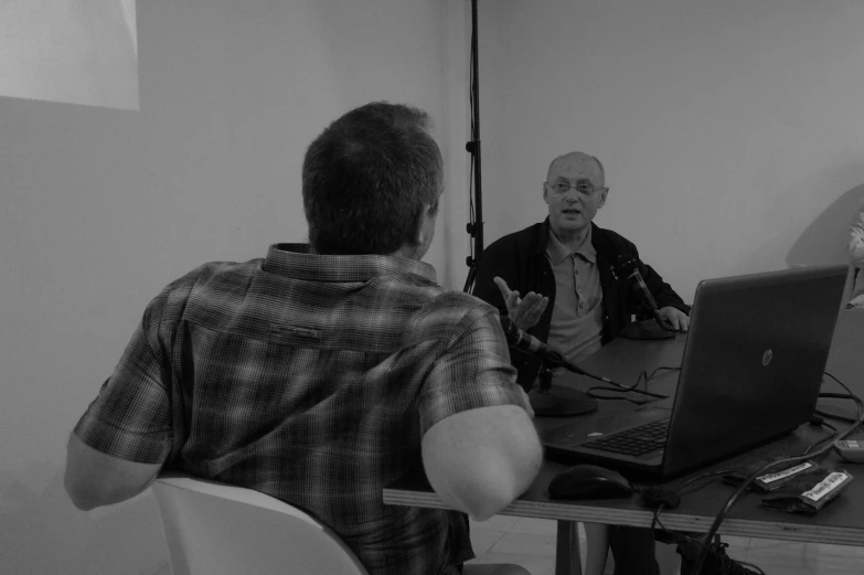 two men in front of a laptop on a table