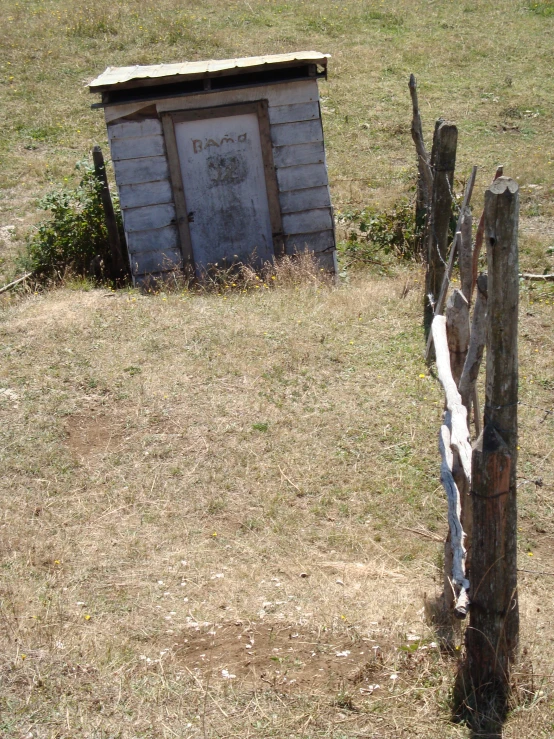 there is an outhouse in the grass and fence