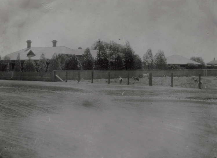 two people walk down the road in a fenced off area