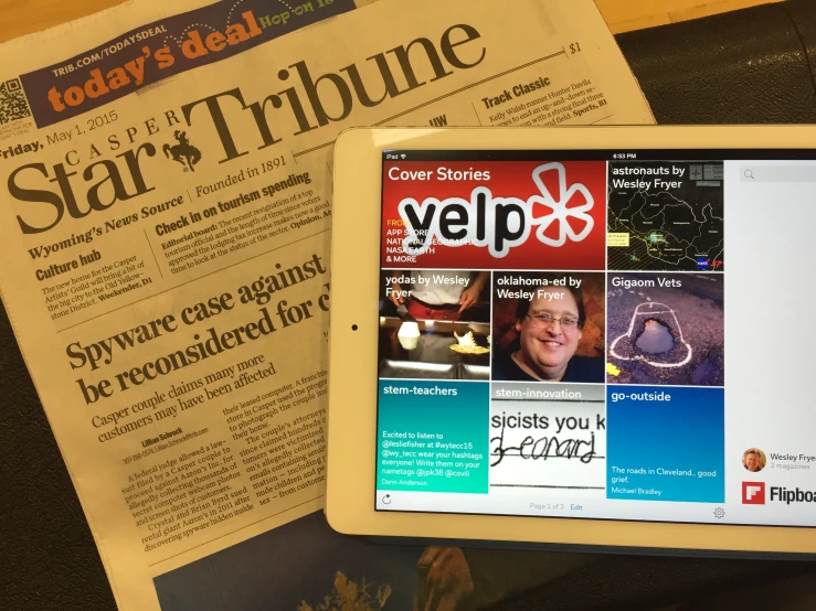 a close up of a person's ipad with a newspaper nearby