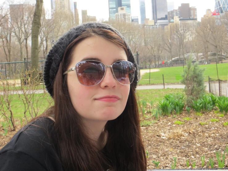 a young woman in sunglasses and hat in the park