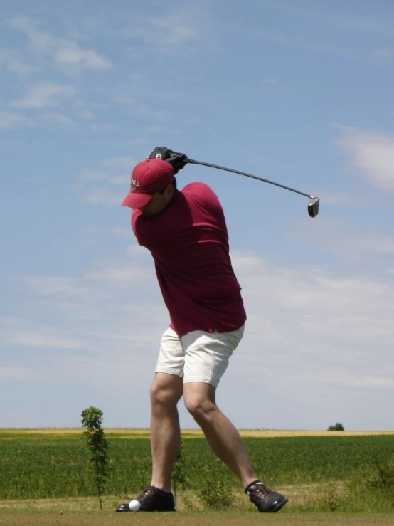 a man in red shirt playing golf on grass