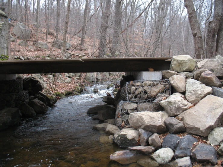 a wooden bridge over a river filled with rocks