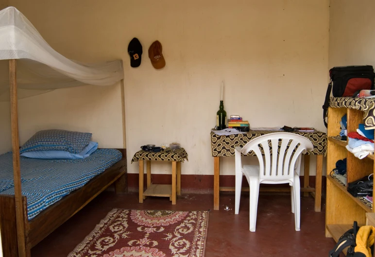 a bed with a white chair and two blue bedspreads