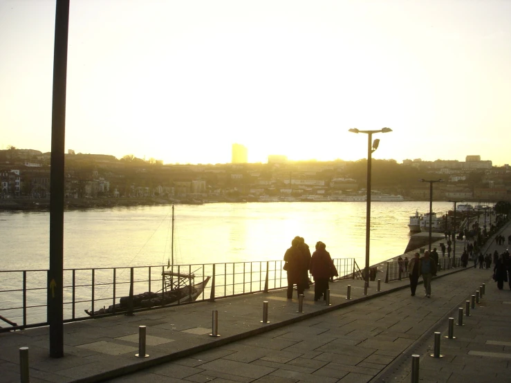 two people walking down a pier as the sun is setting