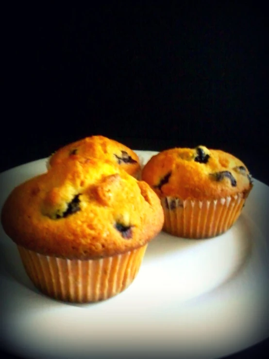 two muffins are sitting on a plate with dark background