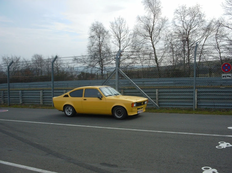 a yellow car is stopped next to the fence