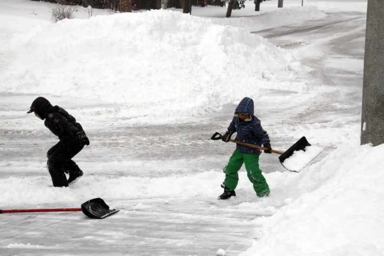 a boy is standing in snow with a shovel