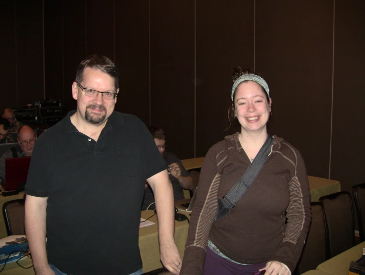 two people standing next to each other in front of chairs