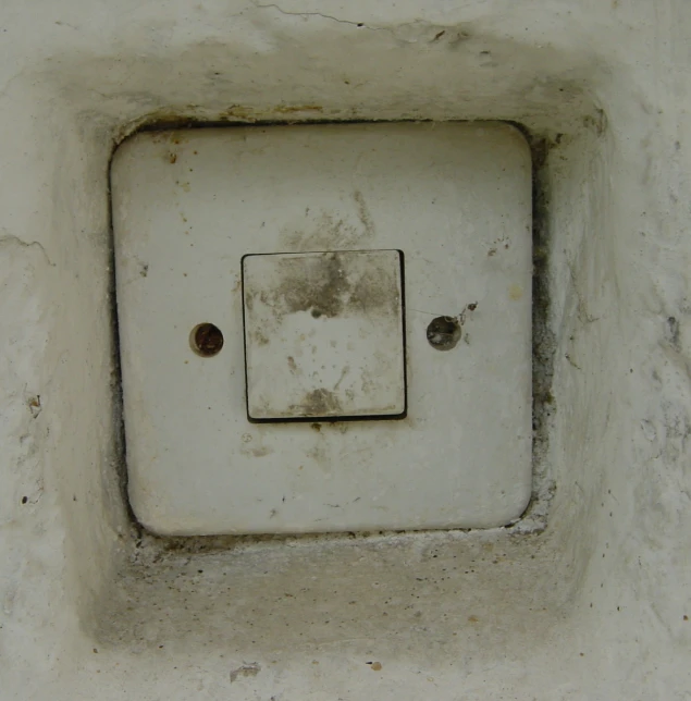 a white electrical switch in a rough and worn out area