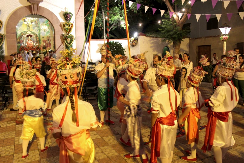 people dressed in elaborate attire dance on a brick patio