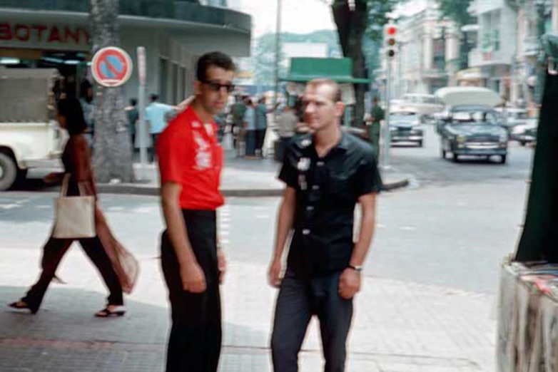 two men standing next to each other on a sidewalk