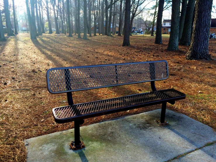 a park bench sits in the middle of some brown grass