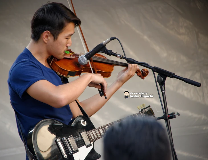 a man holding an acoustic guitar near a microphone