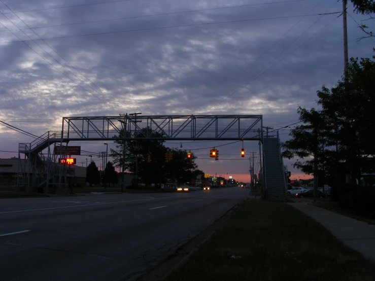 some street lights on a long road under a cloudy sky