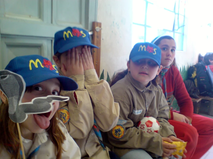 three children wearing mcdonald's hats, sitting in a group