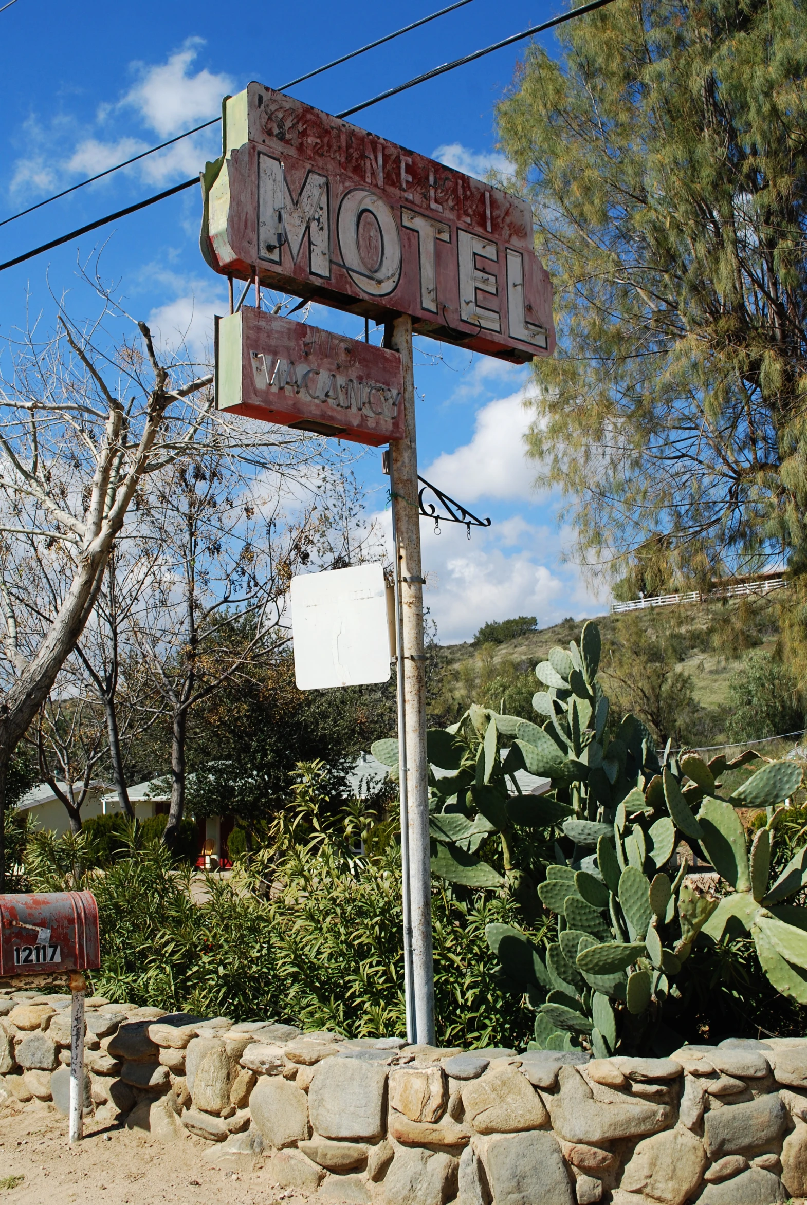 a motel sign is displayed outside near some trees