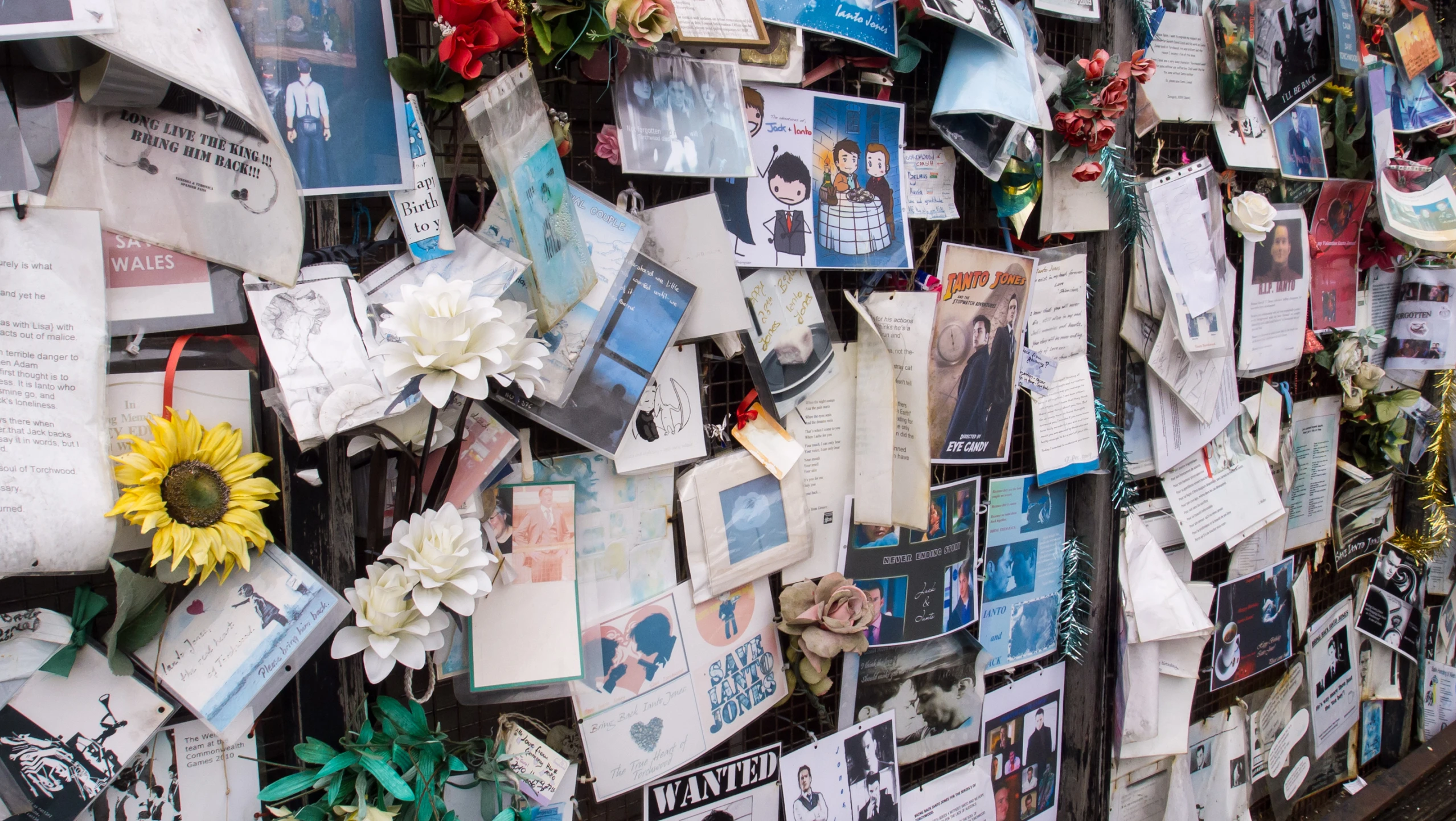 a wall that has pictures and paper pictures pinned to it