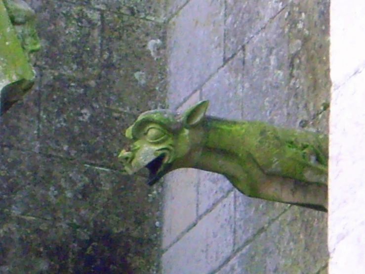 a statue with its mouth open, on the outside of a building
