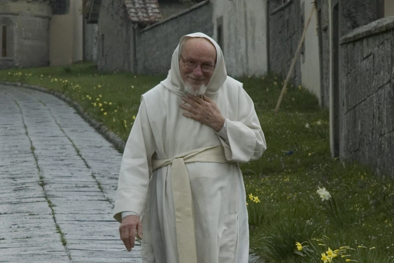 the old man walks in the street dressed in white robes