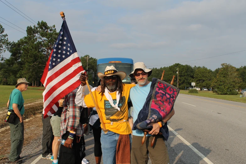 two men holding flags and a bus on the side of a road