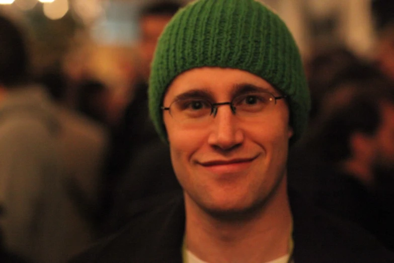 man wearing green beanie with white shirt in middle of crowded area