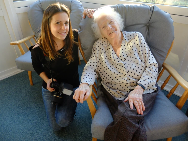 two women posing for a picture and one is holding a camera