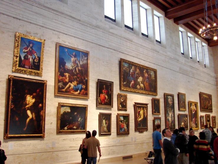 people in a large room with paintings on the wall