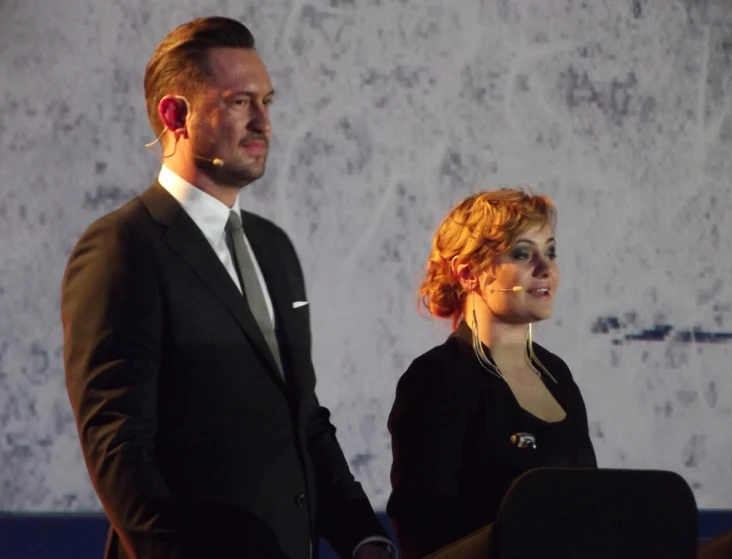 a woman and man holding hands during a speech