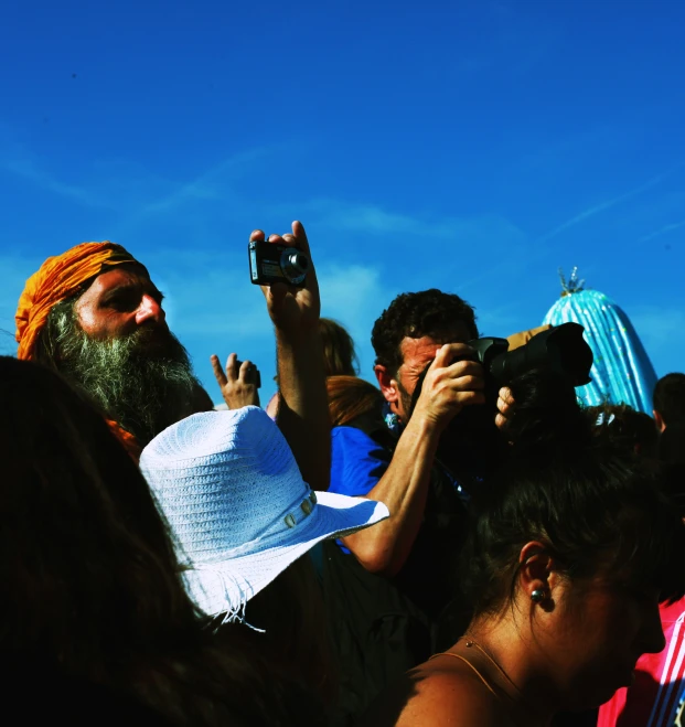 a person with white hat taking pictures on cell phone