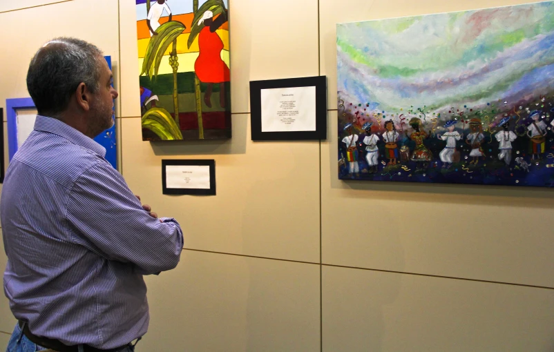 a man looks at artwork hanging on the wall