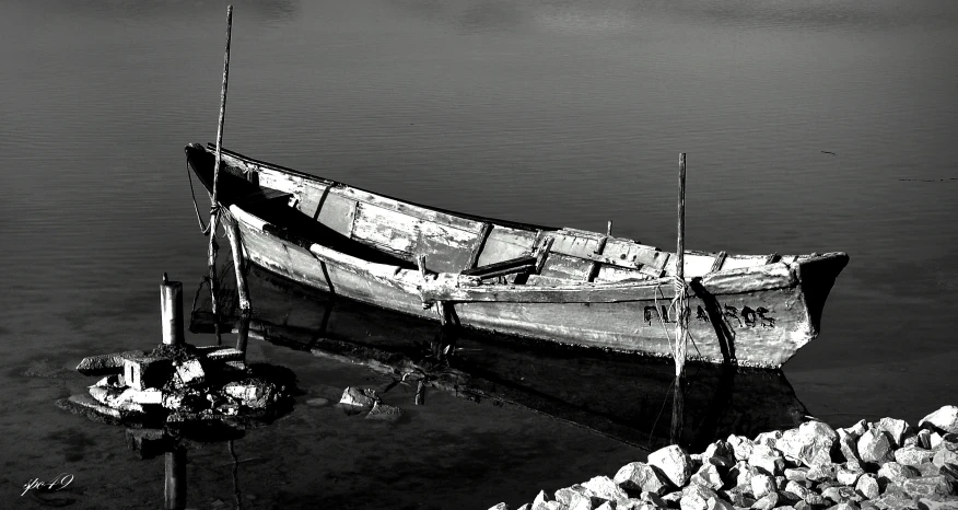 the empty boat is parked on the rock by the water