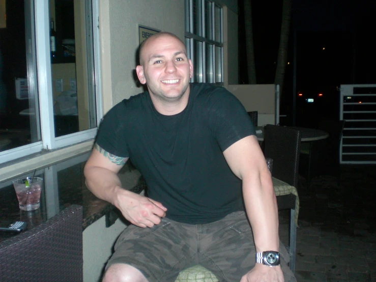 a man is sitting down smiling by a patio