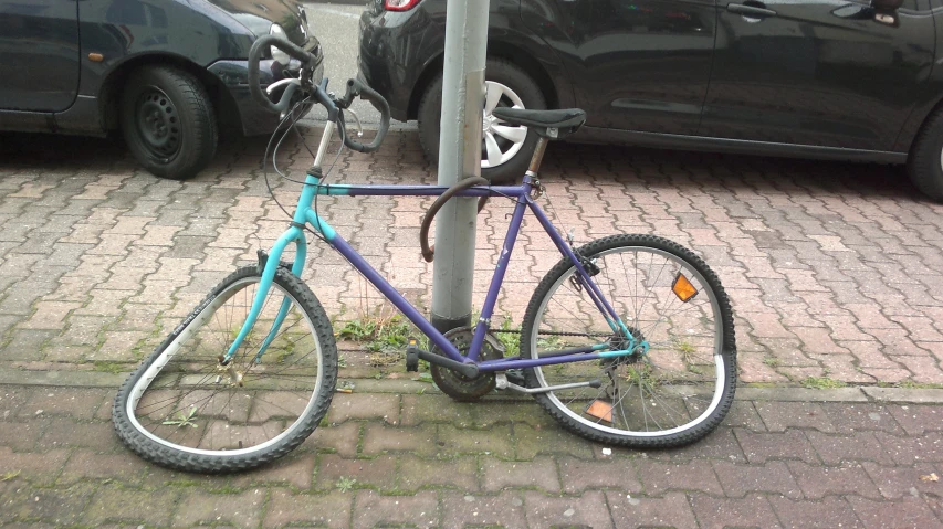 bicycle  to a pole in front of some cars