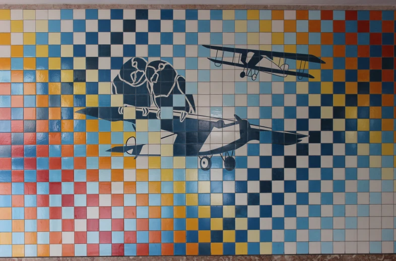 a wall decorated with tiled panels depicting an airplane