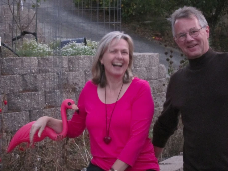 a man and woman are posing with flamingos