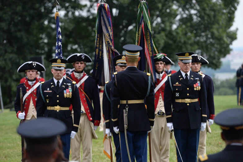 soldiers stand with flags, ready to be led by a man