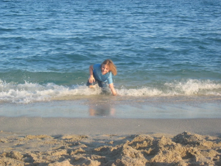 a person playing in the ocean on a sandy beach