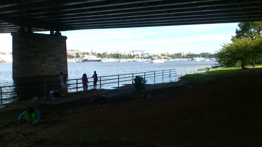 three people standing on the shore watching boats