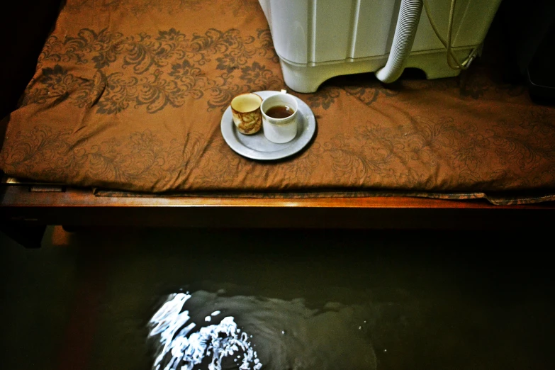 two cups on a plate are beside the commode