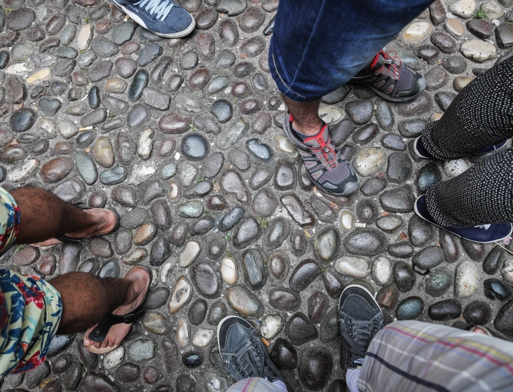 five people stand on a small cobblestone walkway