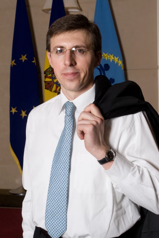 a man is holding his jacket in front of flags